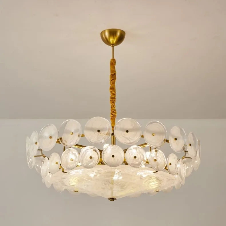 Chandelier with gold frame and white circular shades on a plain background