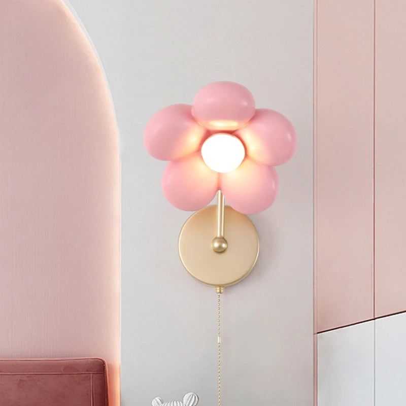 Pink balloon-style wall lamp on a light gray wall with a pink chair and cabinet.