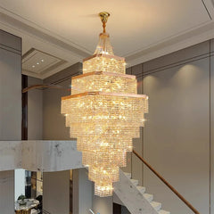 Luxurious crystal chandelier hanging in a modern interior setting with staircase and marble accents.