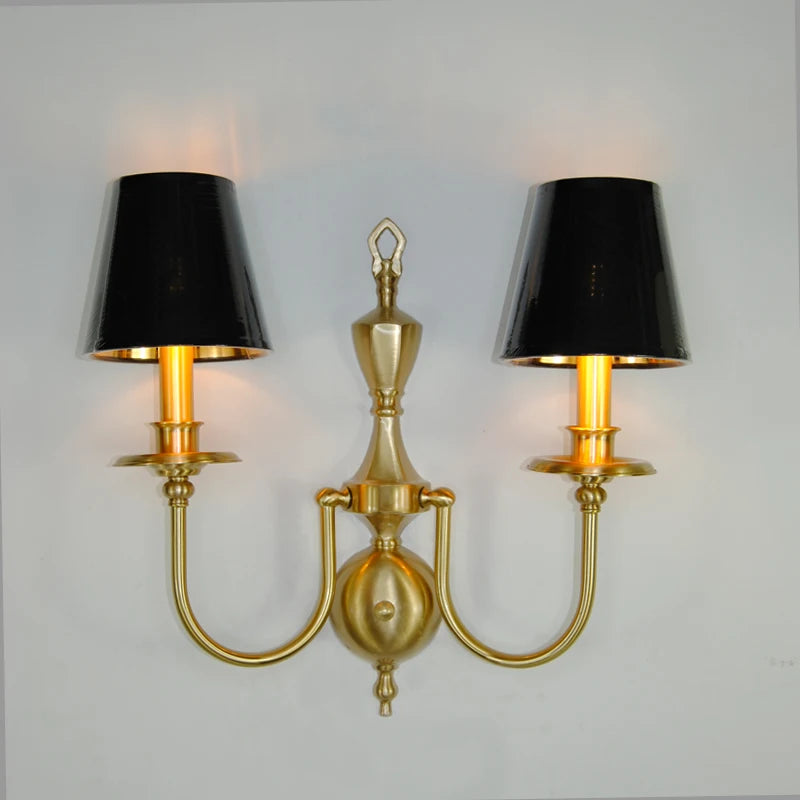 Gold wall sconce with black lampshades on a gray background
