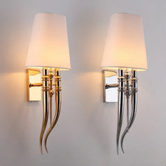 Two wall sconces with decorative metal fixtures on a plain background