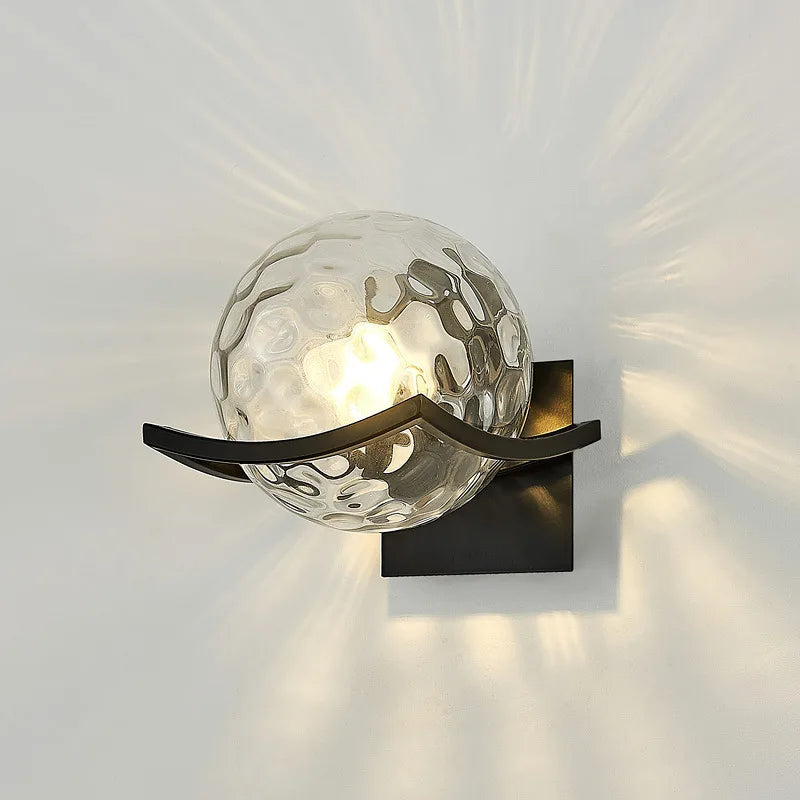 Wall-mounted light fixture with glass shade on a white wall