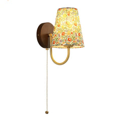Wall-mounted lamp with a floral-patterned shade on a white background. Floral fabric pull chain wall lamp for girls’ bedroom or hallway.