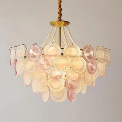 Decorative chandelier with pink and gold elements on a plain background