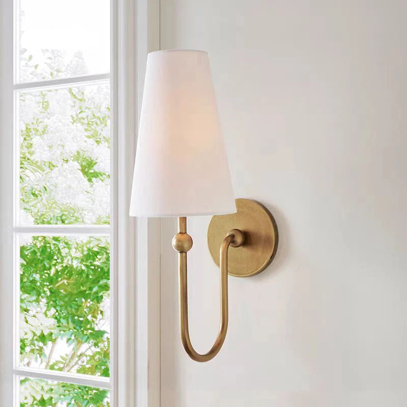 Wall-mounted lamp with white shade and gold fixture on a light gray wall, featuring the brand 'XIFFENTY'.