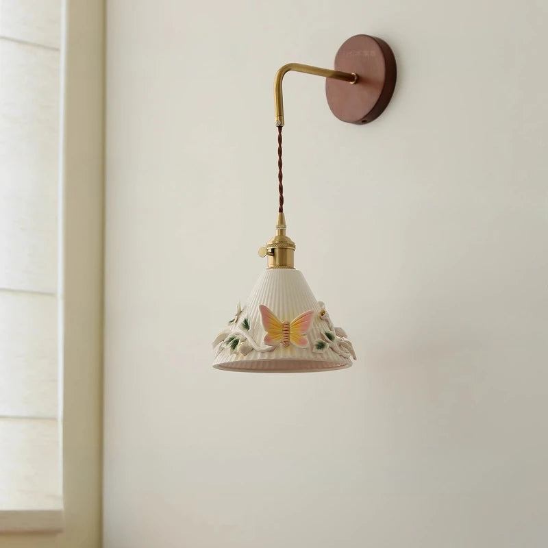 Wall-mounted lamp with decorative shade featuring a butterfly design on a plain wall.