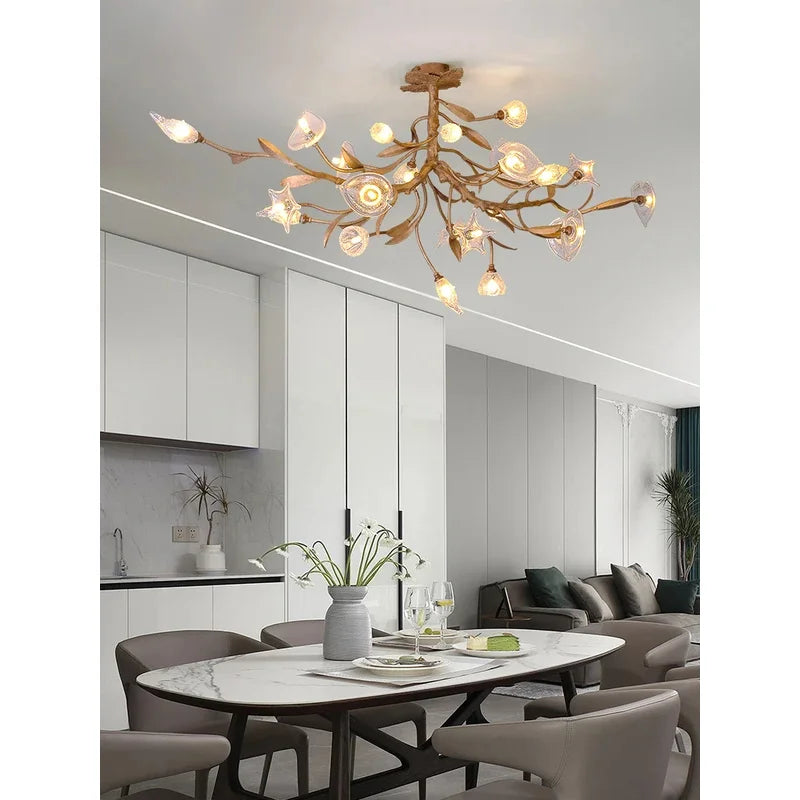 “Gold crystal chandelier with sculptural branches and flower accents”