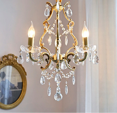 Gold chandelier with crystal accents on a neutral background