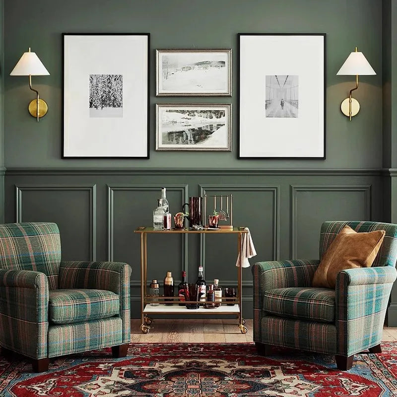 Living room with plaid armchairs, a coffee table, and framed pictures on a green paneled wall.