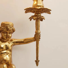 Gold cherub figurine holding a sword against a beige background