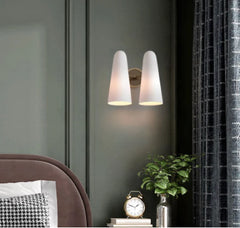 Modern wall sconce with two white lampshades in a room setting.
