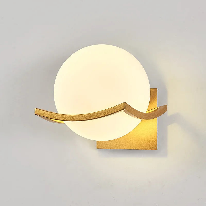Modern wall lamp with gold fixture and white globe on a gray background