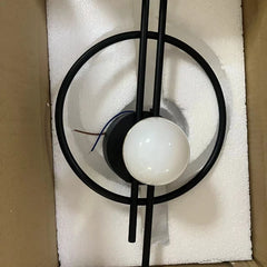 Modern ceiling light fixture with black metal design on a white cushioned surface