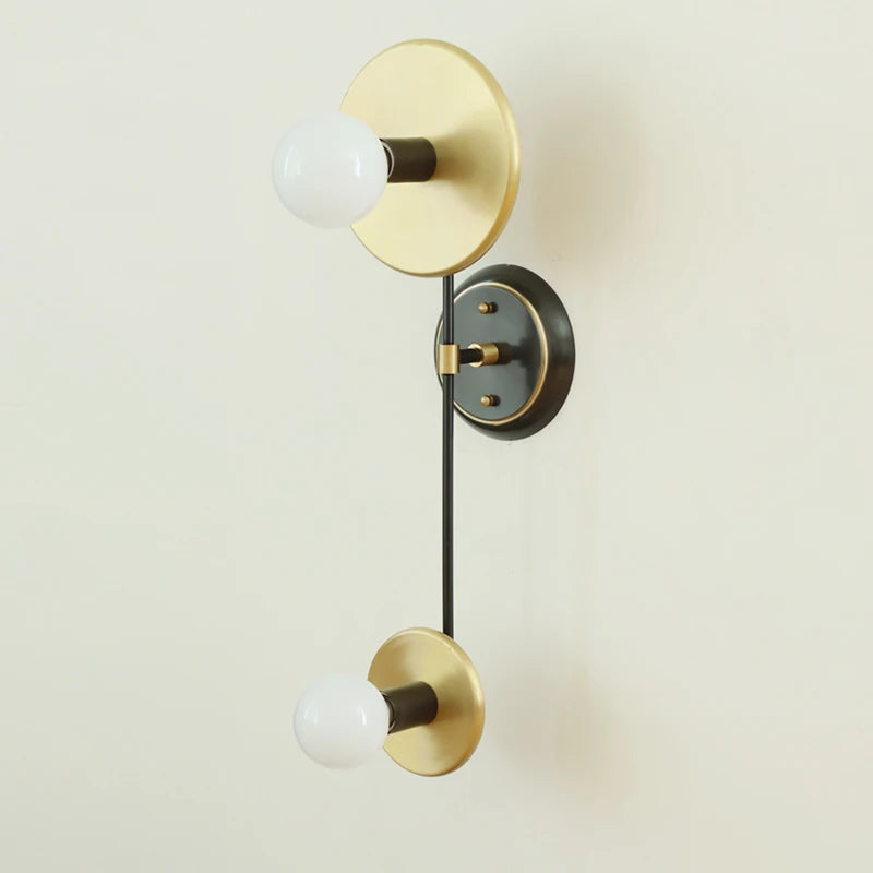 Modern wall sconce with gold and black finish on a light beige background