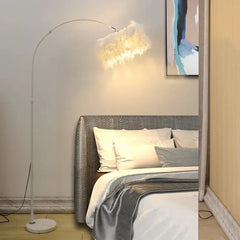 Modern luxury feather floor lamp with silver stand.Bedroom with a bed, floor lamp, and abstract painting on the wall. 