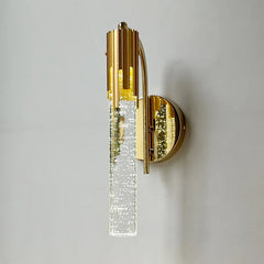 Gold wall sconce with crystal accents on a gray wall