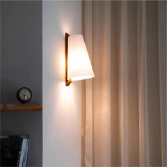 Wall-mounted lamp casting light on a curtain in a room setting