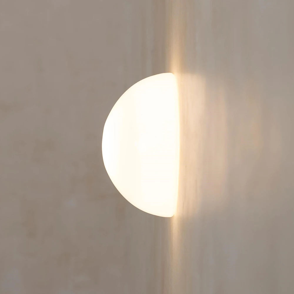 Round light fixture casting a shadow on a textured wall