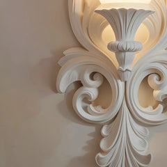 Decorative white wall molding with intricate patterns on a beige wall.