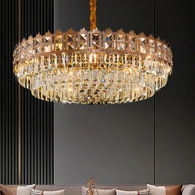 Gold chandelier with crystal accents hanging above a sofa against a dark wall.