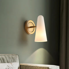 Wall-mounted lamp with a cone-shaped glass shade on a green wall.
