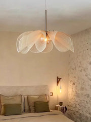 Modern pendant light fixture in a bedroom setting with a stone wall. Soft fabric flower nursery pendant with LED and 3-year warranty