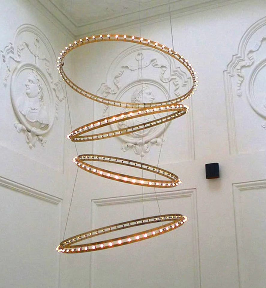 Dramatic spiral metal circle chandelier illuminating a villa staircase lobby