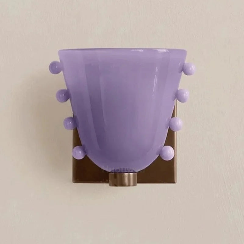 Purple wall sconce with decorative balls on a beige wall