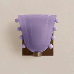 Purple wall sconce with decorative balls on a beige wall