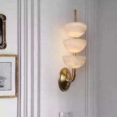 Wall-mounted lamp with gold fixture and glass shades on a light gray wall.
