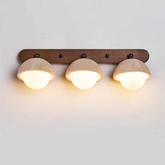 “Three-light travertine stone wall lamp mounted on a wood bar with warm glow.”