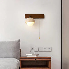 “Travertine stone wall lamp with wood backplate above a bedside table.”