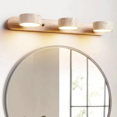 “Travertine and wood vanity wall lamp mounted above a round bathroom mirror.”