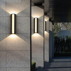 “Black vertical up-and-down LED wall lamp illuminating a stone exterior wall.”