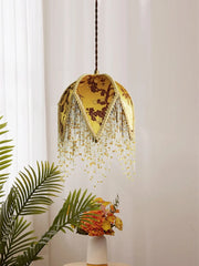 “Artisan fabric pendant lamp with decorative gold or green fringe”