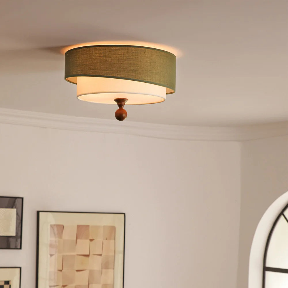 “Green fabric drum ceiling light in a bright room, casting a soft ambient glow.”