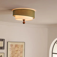 “Green fabric drum ceiling light in a bright room, casting a soft ambient glow.”